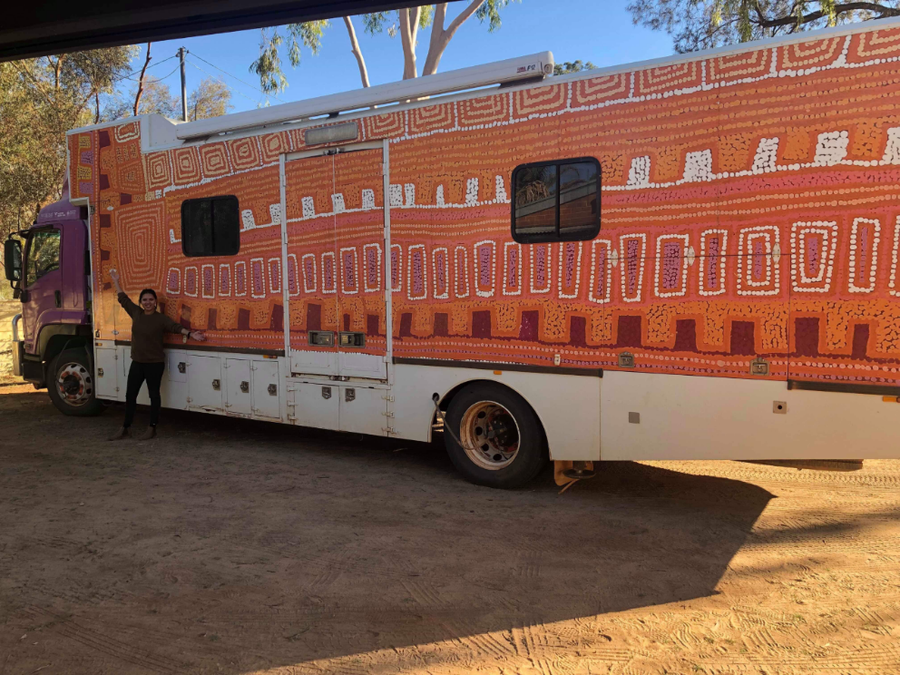 Student in front of Purple House Bus