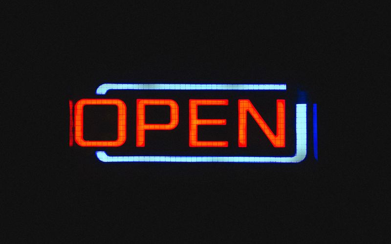Illuminated neon sign of the word 'open' on a dark background