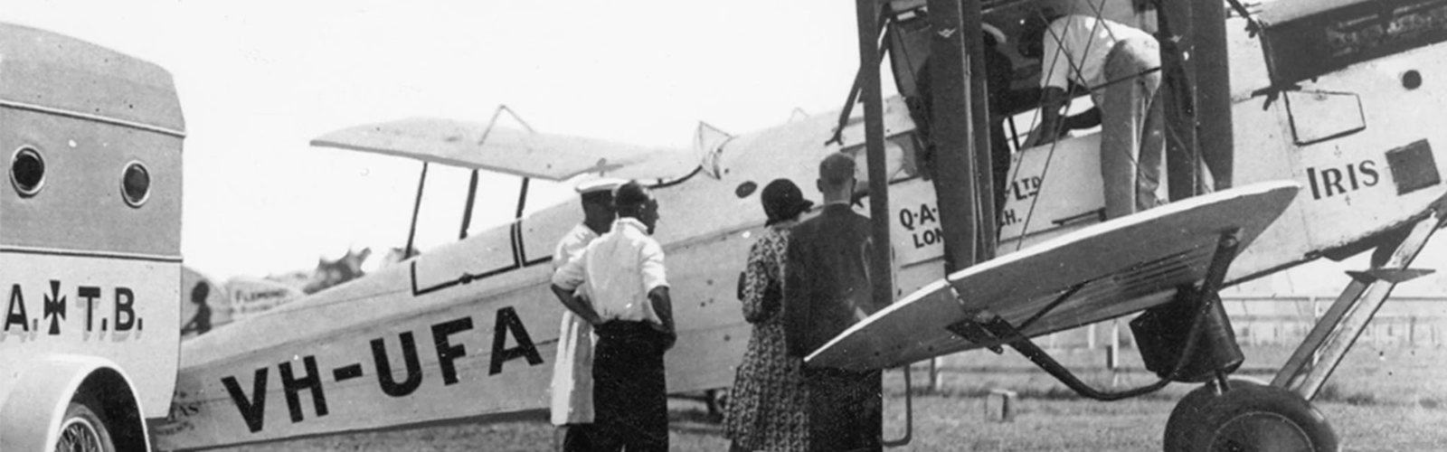 four people standing in front of a plane next to an ambulance, image is in black and white indicating it is from a long time ago