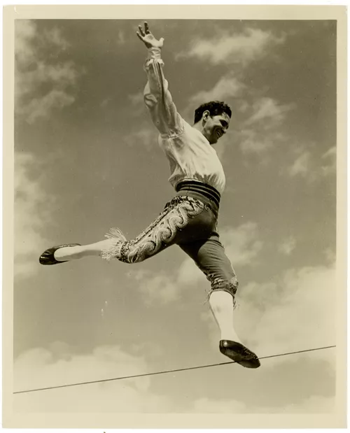 A black and white photo of a man walking a tightrope