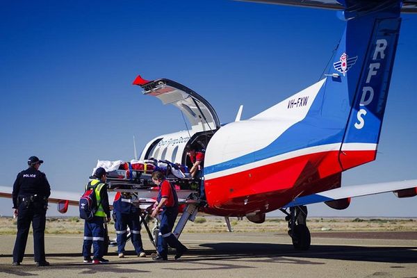 Man attending to patient next to plane