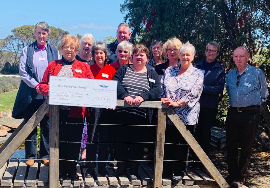 A group of people holding an oversized cheque smile at the camera. 