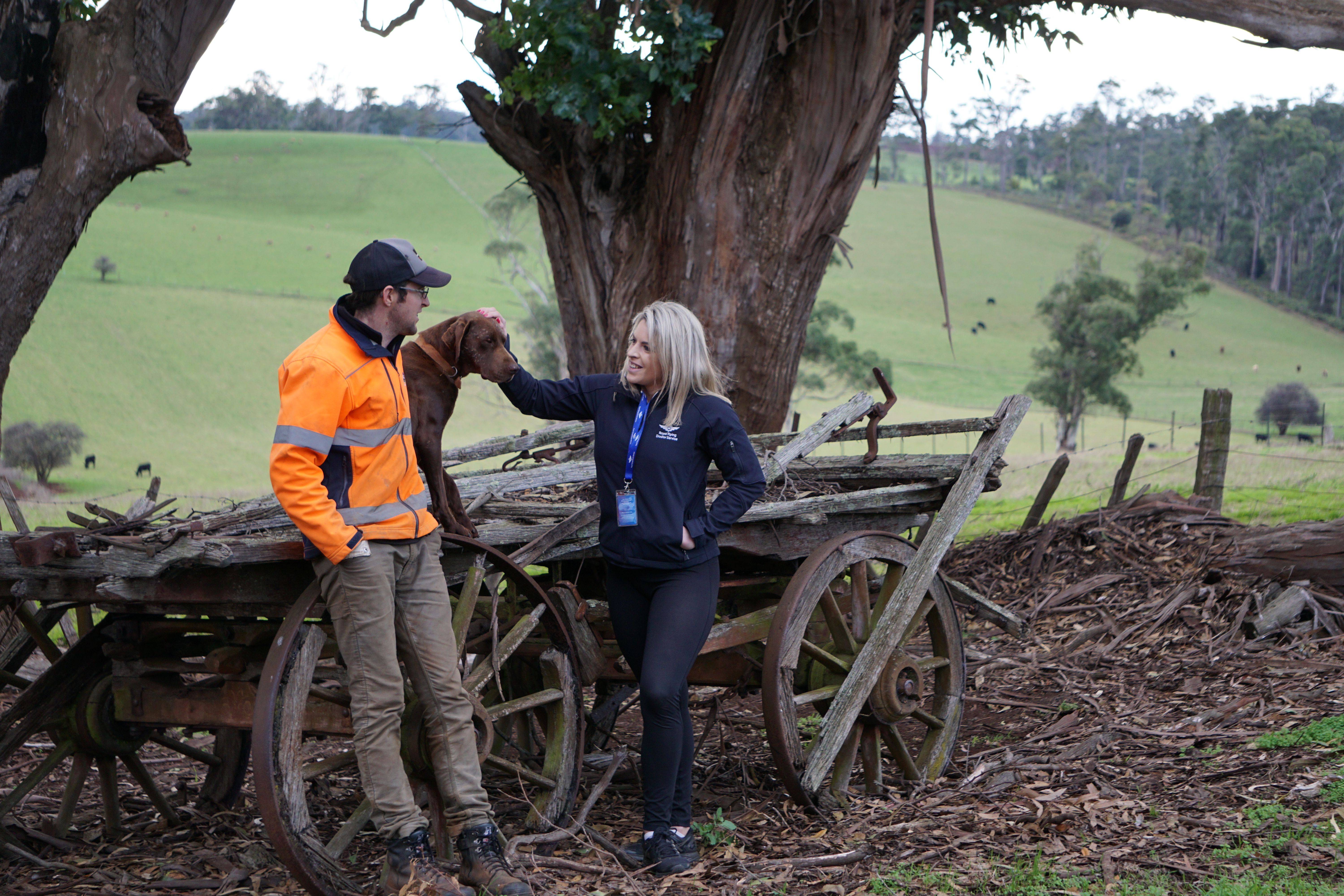 Harriet from RFDS Tasmania with a sheep farmer and his dog on his land.