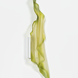 A green glass feature object that seems like a piece of textile hanging on a white wall.