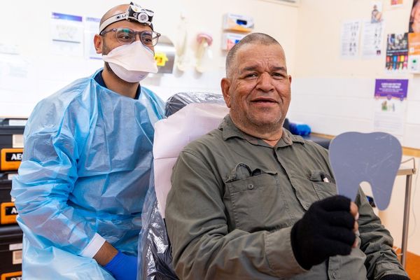 Dr Vai is pictured with a patient in a dentist's chair in Alice Springs