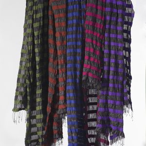 Photo of a range of bright coloured silk scarves hanging from a stick