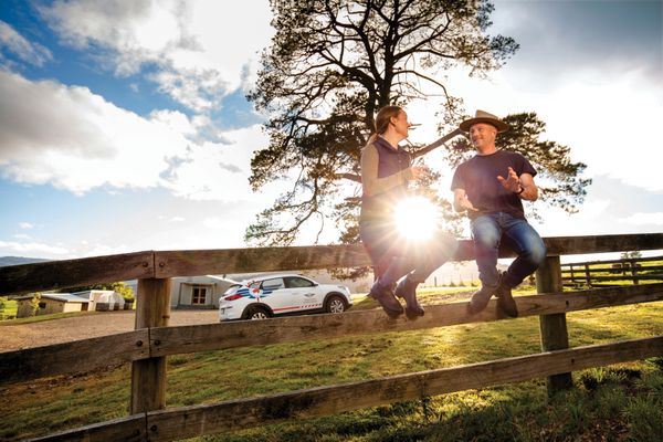 Two people sit on a fence talking