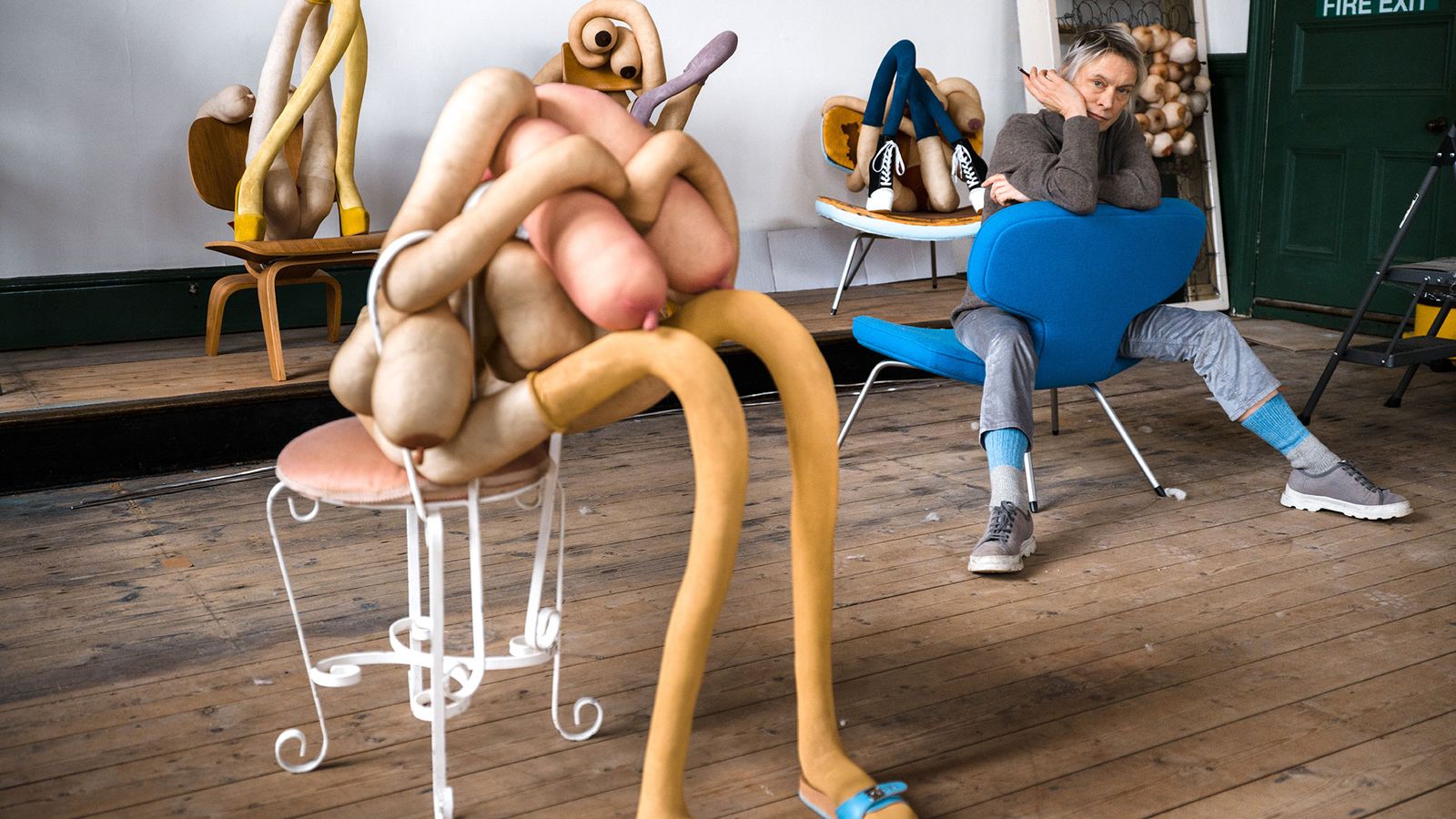 photo of artist Sarah Lucas sitting amongst her seated sculptures