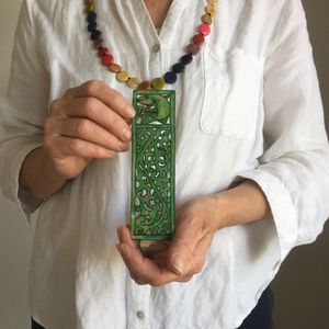 A delicately carved green book mark is held by a female