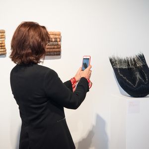 Woman takes a photo of an artwork in a gallery